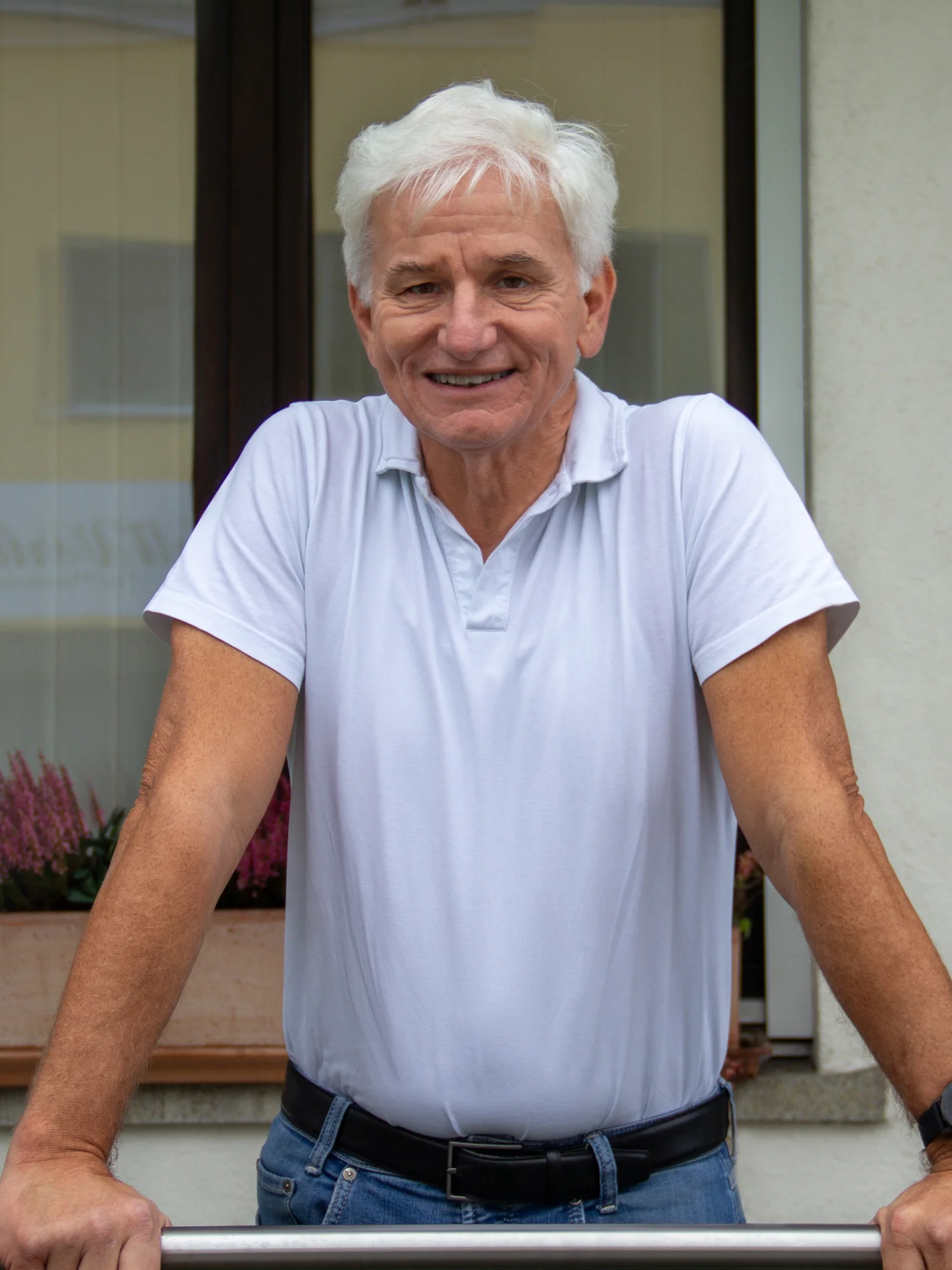 Dr. Hubert Dörler lehnt lächelnd am Geländer vor der Praxis